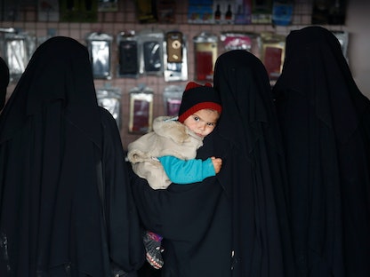 امرأة من نساء "داعش" تحمل طفلة داخل متجر في مخيم الهول في سوريا - 8 يناير 2020 - REUTERS