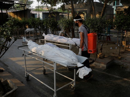 عامل بلدية يرش مطهراً على جثث الضحايا الذين لقوا حتفهم بسبب فيروس كورونا، في محرقة جثث في نيودلهي، الهند. 10 مايو 2021 - REUTERS
