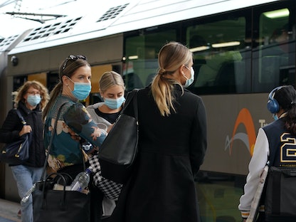 مسافرون يرتدون أقنعة الوجه الواقية في المحطة المركزية للقطار، بعد تنفيذ لوائح الصحة العامة الجديدة، حيث تكافح المدينة تفشي فيروس كورونا في سيدني. - REUTERS
