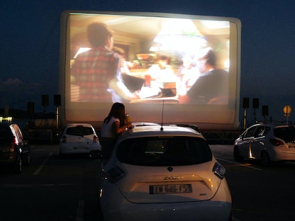 مشاهدون يستمتعون بمشاهدة فيلم في إحدى دور عرض سينما السيارات، التي برزت كحل لمواجهة قيود التباعد الاجتماعي في فرنسا - AFP