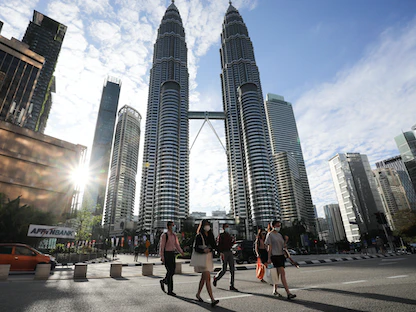 أشخاص يرتدون أقنعة واقية أمام برجي "بتروناس" في العاصمة الماليزية كوالالمبور - 11 يناير 2021 - REUTERS