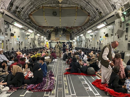 عائلات أفغانية داخل إحدى الطائرات العسكرية الأميركية خلال عمليات الإجلاء من مطار كابول، 19 أغسطس 2021 - AFP