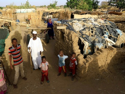 أسرة سودانية نازحة تقف خارج مأواها المؤقت داخل مخيم كلمة للنازحين داخلياً في دارفور، السودان- 26 أبريل 2019. - REUTERS
