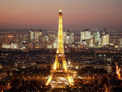 منظر عام يُظهر برج إيفل المضاء وأفق منطقة لا ديفينس التجارية ليلاً في باريس - REUTERS