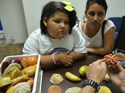 طفلة تستمع لطبيب يتحدث عن التغذية بمدينة ميديلين شمال غرب كولومبيا. 25 فبراير 2015 - AFP