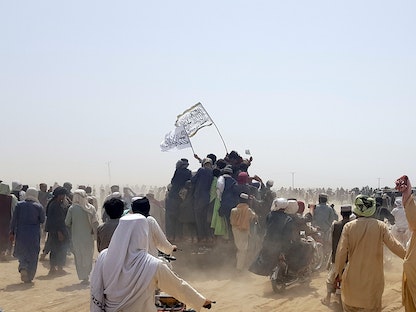 أشخاص يقفون على مركبة يحملون أعلام طالبان، بينما يتجمع الناس بالقرب من نقطة عبور بوابة الصداقة في بلدة شامان الحدودية الباكستانية الأفغانية، باكستان. 14 يوليو 2021 - REUTERS