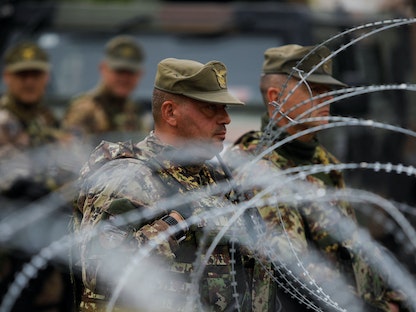 أعضاء من قوة حلف الناتو في كوسوفو يقفون خلف أسلاك شائكة في بلدة ليبوسافيتش شمالي البلاد. 1 يونيو 2023 - REUTERS