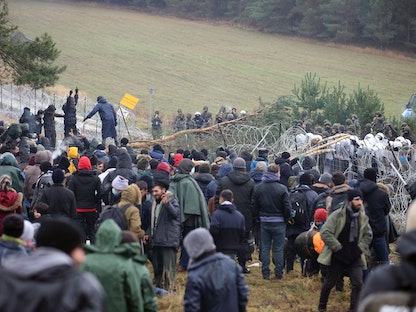 مهاجرون يتجمعون بالقرب من سياج من الأسلاك الشائكة في محاولة لعبور الحدود إلى بولندا في منطقة جرودنو في بيلاروسيا، 8 نوفمبر 2021 - REUTERS