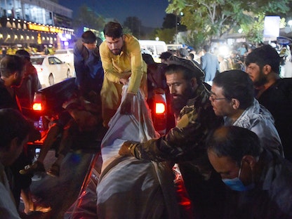 متطوعون وعمال طبيون ينزلون الجثث من شاحنة صغيرة، بعد انفجارين قويين في محيط مطار كابول -26 أغسطس 2021 - AFP
