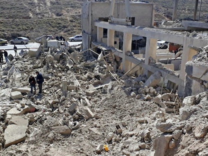 أشخاص يتفقدون مبنى مدمراً في أعقاب الضربات الصاروخية الإسرائيلية قبل الفجر بالقرب من العاصمة دمشق. في 7 مارس 2022. - AFP