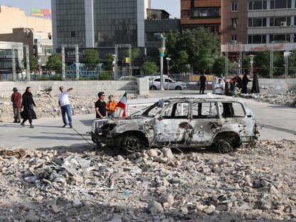 إيرانيون يتفقدون سيارة إسعاف أحرقتها هجمات إسرائيلية في أحد شوارع طهران. 23 يونيو 2025 - REUTERS