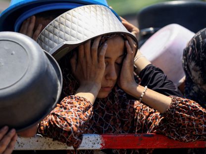 فتاة فلسطينية تتفاعل بينما تنتظر استلام الطعام من مطبخ خيري، وسط أزمة جوع، في مدينة غزة. 22 يوليو 2025 - Reuters