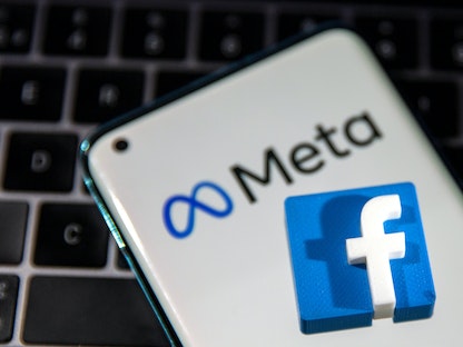 هاتف ذكي يحمل شعاري ميتا وفيسبوك بشكل ثلاثي الأبعاد فوق لوحة مفاتيح كمبيوتر محمول - REUTERS