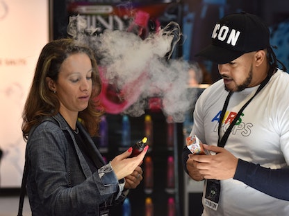 سيدة تدخن السجائر الإلكترونية خلال معرض لبيعها بمدينة برمنجهام في بريطانيا. 7 أكتوبر 2022 - Getty Images