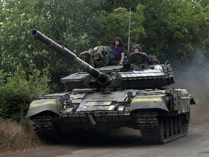 جنود أوكرانيون يركبون دبابة على طريق بمنطقة لوغانسك الشرقية، 23 يونيو 2022 - AFP
