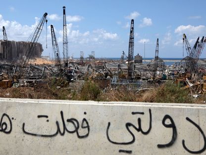 عبارات كتبها ناشطون على جدار مقابل مرفأ بيروت المدمر تُحمّل السلطة مسؤولية الانفجار - AFP