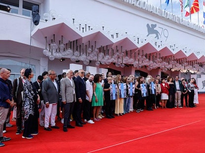 عدد من صناع السينما في العالم ينظمون وقفة على السجادة الحمراء في مهرجان فينيسيا السينمائي الدولي للتضامن مع زملائهم الذين يتعرضون لمضايقات حول العالم، إيطاليا، 9 سبتمبر 2022. - labiennale.org