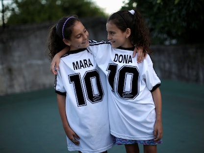 التوأمتان مارا ودونا يرتديان الرقم "10" المفضل للاعب الأرجنتيني الراحل مارادونا، في منزلهما ببيونس آيريس - REUTERS