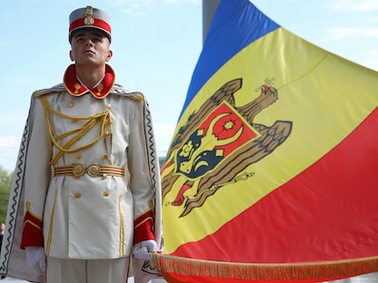 عنصر من حرس الشرف يحمل علم مولدوفا خلال إحياء "يوم علم الدولة" في العاصمة كيشيناو - 27 إبريل 2022. - REUTERS