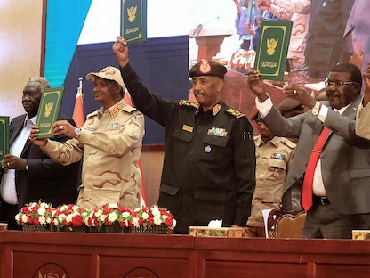 رئيس المجلس السوداني عبد الفتاح البرهان ونائبه محمد حمدان دقلو يرفعان وثائق الاتفاق الإطاري إلى جانب القادة المدنيين، في الخرطوم - 5 ديسمبر 2022 - AFP