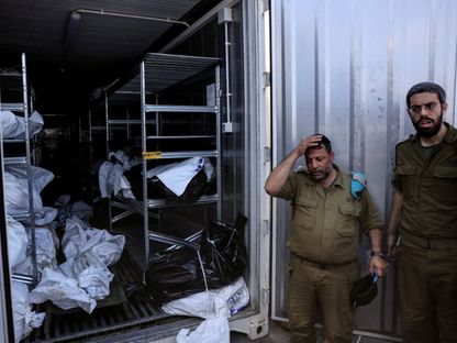 ضباط إسرائيليون يقفون بجانب جثث قبل استدعاء أقاربهم للتعرف عليهم في أعقاب هجوم شنته فصائل فلسطينية في محيط قطاع غزة. 13 أكتوبر 2023 - Reuters