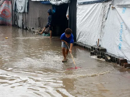 أطفال فلسطينيون نازحون يحاولون دفع مياه الأمطار بعيداً عن الخيام في مدينة غزة. 25 نوفمبر 2025 - Reuters