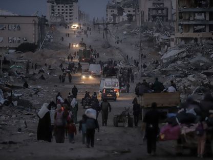 نازحون فلسطينيون أمام مبان مدمرة أثناء عودتهم إلى شمال قطاع غزة. مدينة غزة. 28 يناير 2025 - Bloomberg