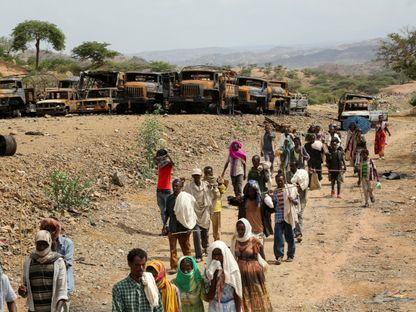 سكان في جنوب وسط تيجراي يسيرون بجوار عشرات المركبات المحترقة. إثيوبيا. 10 يوليو 2021 - Reuters