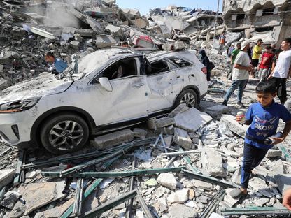 طفل فلسطيني يسير بجوار سيارة متضررة في موقع غارة جوية إسرائيلية على منزل في مدينة غزة. 27 يونيو 2025 - REUTERS