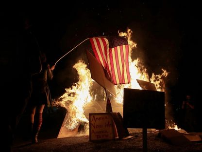 متظاهر يشعل النار في العلم الأميركي خلال احتجاجات ضد عنف الشرطة في بورتلاند بولاية أوريجون الأميركية. 27 يوليو 2020 - REUTERS