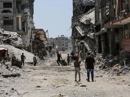 فلسطينيون وسط الدمار بعد انسحاب الجيش الإسرائيلي من حي الزيتون جنوب مدينة غزة. 17 مايو 2024 - AFP