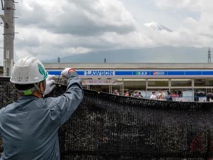عامل يقوم بتثبيت حاجز لمنع السائحين من رؤية جبل فوجي في بلدة فوجيكاواجوتشيكو باليابان. 21 مايو 2024. - AFP