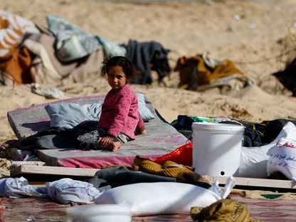 طفل نازحة مع عائلتها تجلس على الأرض في مخيم رفح جنوبي غزة وسط استمرار الغارات الإسرائيلية على مختلف أنجاء القطاع- 10 يناير 2024 - Reuters