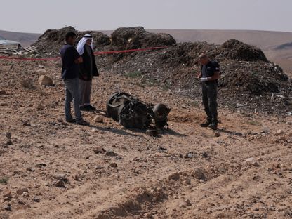 ضابط شرطة وسكان يتفقدون بقايا صاروخ إيراني وفقاً للسلطات الإسرائيلية قرب مدينة عراد جنوب شرق إسرائيل. 14 أبريل 2024 - REUTERS