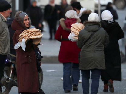 نساء يحملن الخبز أثناء عبورهن أحد الشوارع بعد الإطاحة بنظام الرئيس السوري بشار الأسد في العاصمة دمشق. 6 يناير 2025 - Reuters