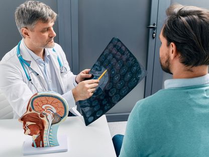 طبيب أعصاب يوضح لمريض نتائج الفحص بالأشعة المقطعية على المخ. 9 أغسطس 2023 - AFP