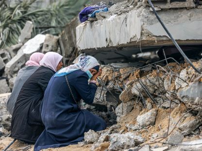 فلسطينيات يبكين عند أنقاض منزل دمرته غارة إسرائيلية في رفح بجنوب قطاع غزة في فلسطين. 21 ديسمبر 2023 - AFP