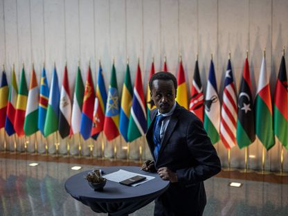 رجل يدون ملاحظات على طاولة أمام أعلام الدول أعضاء الاتحاد الإفريقي في مقر الاتحاد بأديس أبابا. 15 فبراير 2024 - AFP