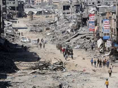 فلسطينيون يتفقدون مباني دمرتها القوات الإسرائيلية في خان يونس جنوب قطاع غزة- 7 أبريل 2024 - AFP
