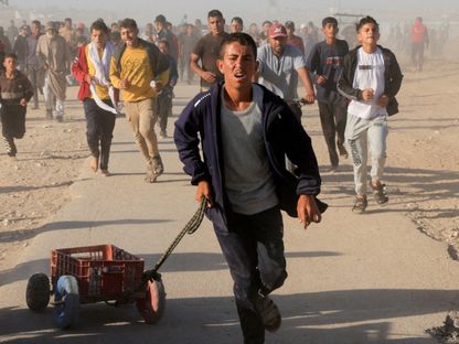 فلسطينيون يركضون لجمع إمدادات الإغاثة من (مؤسسة غزة الإنسانية) في خان يونس جنوب قطاع غزة. 29 مايو 2025 - REUTERS