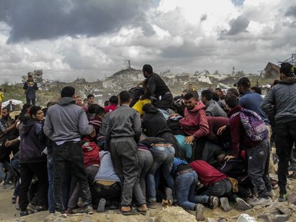 فلسطينيون يتدافعون على شاطئ غزة في محاولة للحصول على المساعدات الغذائية التي يتم إسقاطها عبر الطائرات الحربية على القطاع. 25 مارس 2024 - AFP