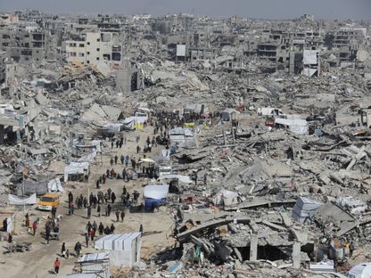 فلسطينيون يسيرون بين أنقاض المنازل والمباني التي دمرها الجيش الإسرائيلي في مخيم جباليا للاجئين شمالي قطاع غزة. 29 يناير 2025 - REUTERS