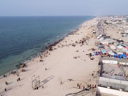 فلسطينيون على ساحل غزة في انتظار المساعدات الإنسانية التي يتم إسقاطها بالطائرات الحربية على القطاع. 26 فبراير 2024 - Reuters
