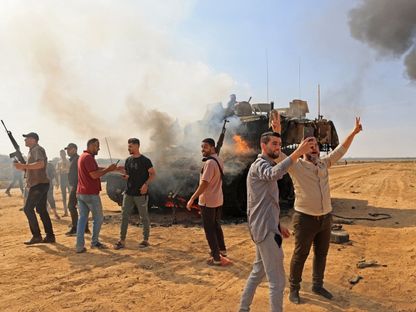 مقاتلو حركة "حماس" يسيطرون على دبابة إسرائيلية عقب العبور الجدار الفاصل بين قطاع غزة وإسرائيل. 7 أكتوبر 2023 - AFP