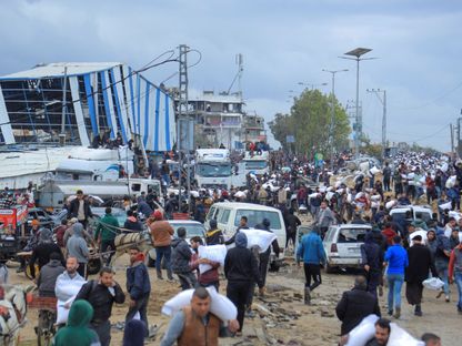 فلسطينيون يحملون أكياس دقيق حصلوا عليها من شاحنة مساعدات بالقرب من نقطة تفتيش إسرائيلية في مدينة غزة. 27 يناير 2024 - REUTERS