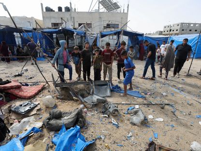فلسطينيون يتفقدون موقع غارة جوية إسرائيلية على خيمة تؤوي نازحين في دير البلح وسط قطاع غزة. 17 مايو 2025 - Reuters