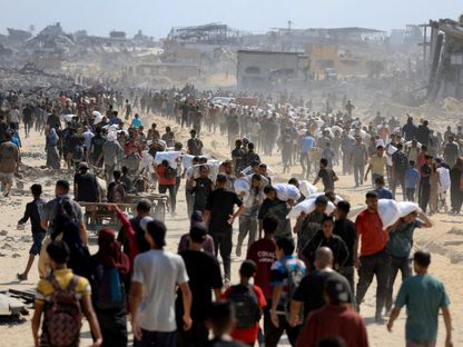 فلسطينيون يتجمعون وهم يحملون إمدادات مساعدات إنسانية وسط أزمة جوع، في بيت لاهيا شمال قطاع غزة. 20 يوليو 2025 - Reuters