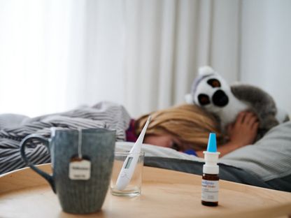 طفل مريض في ألمانيا بجانبه مقياس حرارة للحمى ورذاذ للأنف وفنجان شاي. 11 سبتمبر 2021 - AFP