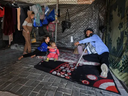 فلسطيني نازح يجلس داخل خيمته مع أطفاله بعد أن فقد مصدر دخله وأصبح معتمداً بالكامل على المساعدات الإنسانية في مدينة غزة. 5 يناير 2026 - REUTERS