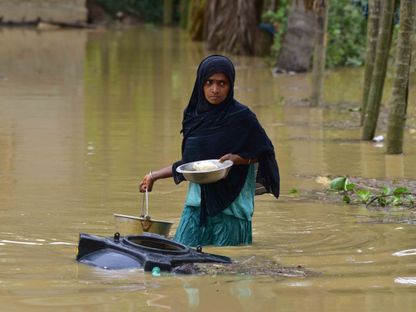 امرأة تحمل تخوض في مياه الفيضانات في الهند. 31 مايو 2024 - AFP